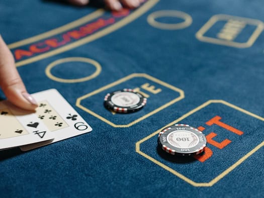 Hände am Casinotisch mit Spielkarten und Jetons