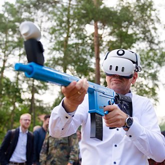 Mit einem Übungsgewehr und einer Virtual-Reality-Brille übt Regierungschef Lies virtuell den Abschuss feindlicher Drohnen. / Foto: Michael Matthey/dpa