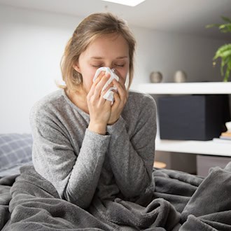 Person mit Taschentuch auf dem Bett im Schlafzimmer