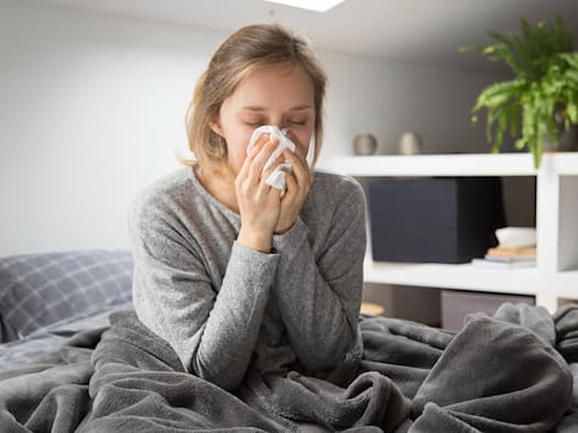Person mit Taschentuch auf dem Bett im Schlafzimmer