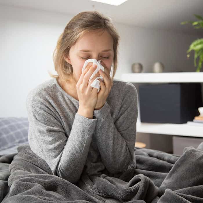 Person mit Taschentuch auf dem Bett im Schlafzimmer