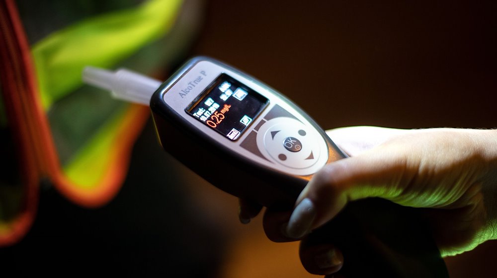 Eine Frau hält einen Alkoholtester in der Hand. / Foto: Sina Schuldt/dpa