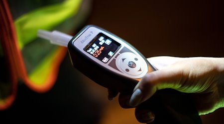 Eine Frau hält einen Alkoholtester in der Hand. / Foto: Sina Schuldt/dpa