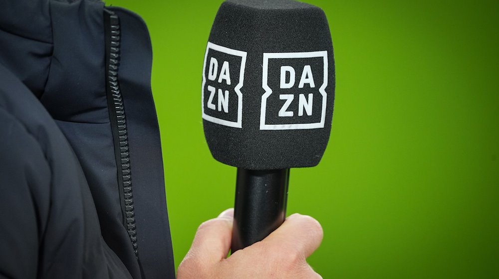 Chef-Trainer Kovac von Wolfsburg hält vor dem Spiel ein Mikrofon mit dem Logo des TV-Senders DAZN. / Foto: Soeren Stache/dpa/Archivbild