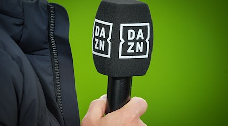 Chef-Trainer Kovac von Wolfsburg hält vor dem Spiel ein Mikrofon mit dem Logo des TV-Senders DAZN. / Foto: Soeren Stache/dpa/Archivbild