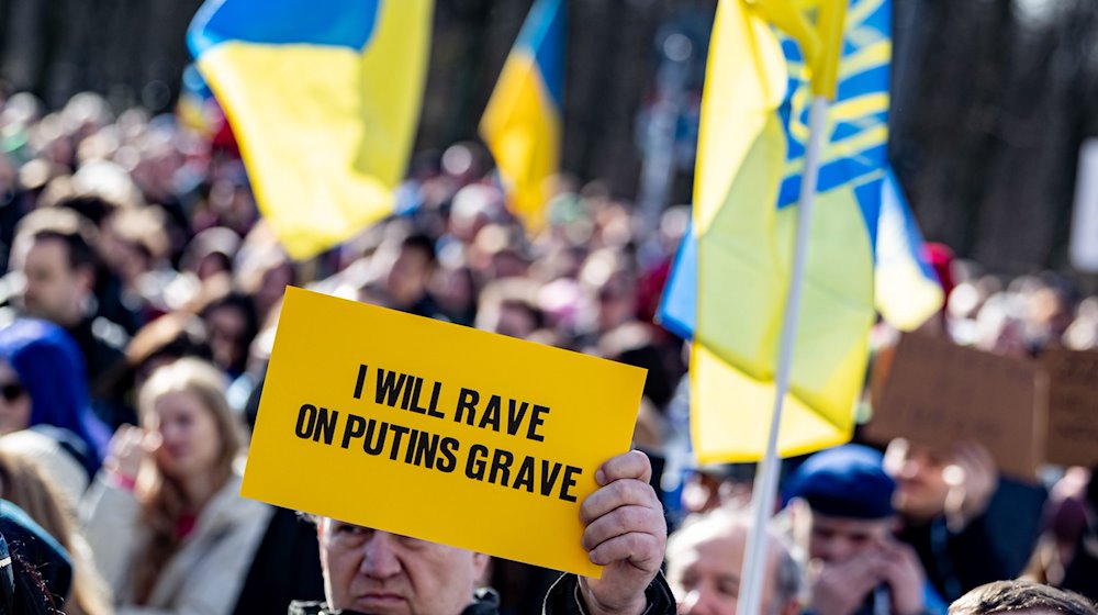 Eine Person hält auf der Solidaritätsdemonstration des Vereins Vitsche «Zusammen Demokratie verteidigen» ein Schild mit der Aufschrift «I will rave on Putins grave» teil. / Foto: Fabian Sommer/dpa