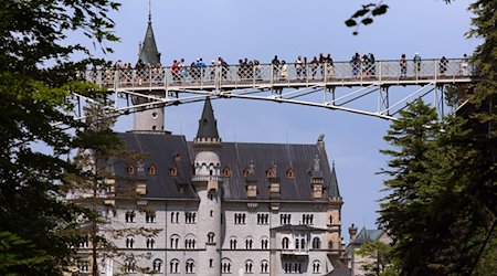 Touristen stehen auf der Marienbrücke vor dem Schloss Neuschwanstein. / Foto: Karl-Josef Hildenbrand/dpa/Archivbild