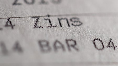 Die Einträge «Zins» und «Bar» sind in einem Sparbuch zu sehen. / Foto: Daniel Karmann/dpa