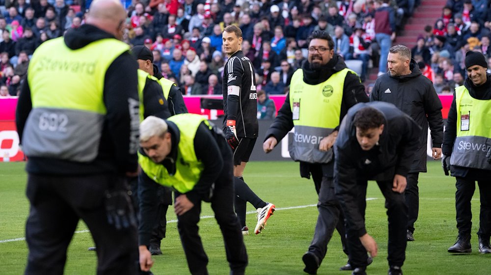 Ordner sammeln Gegenstände vom Spielfled. / Foto: Sven Hoppe/dpa