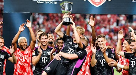 Frans Krätzig (M) hält den Pokal. Der FC Bayern reist im Sommer wieder nach Asien. / Foto: Danial Hakim/AP/dpa