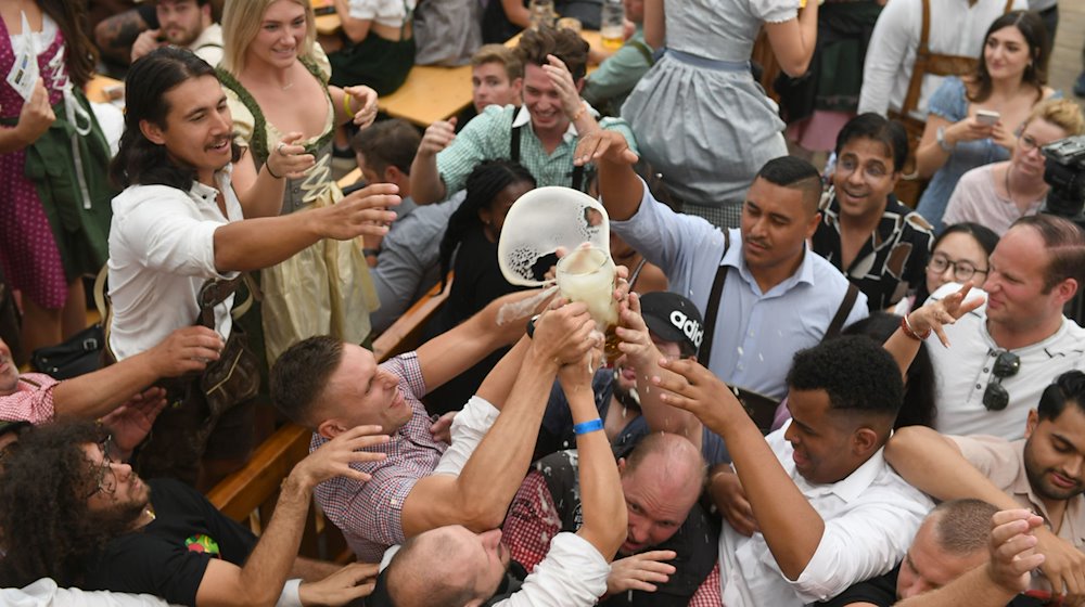 Gäste ringen im Hofbräuzelt um eine Maß Bier. / Foto: Felix Hörhager/dpa