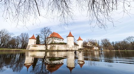 Das Schloss Blutenburg spiegelt sich bei sonnigem Wetter in einem Teich. / Foto: Lino Mirgeler/dpa/Archivbild