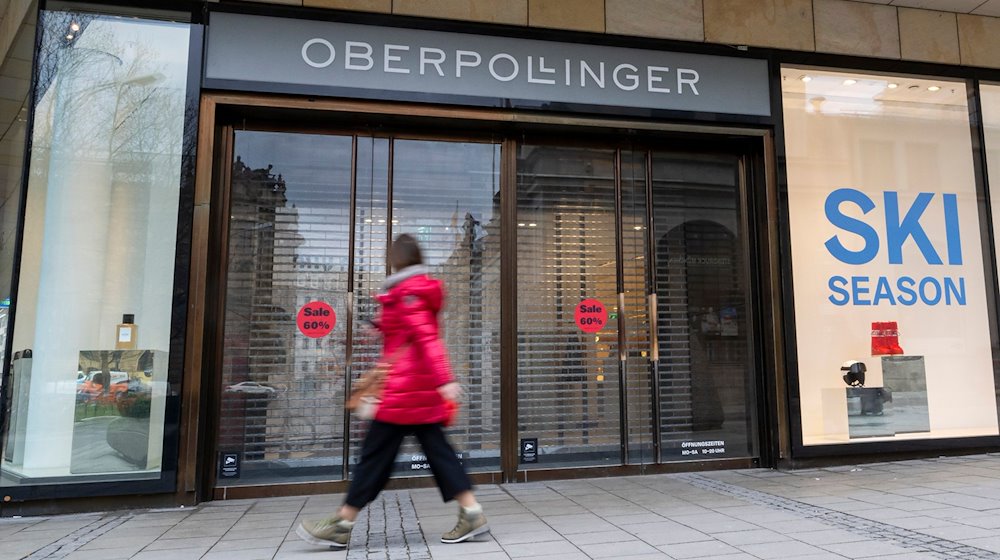 Eine Frau läuft vor Geschäftsöffnung an einem Eingang zum Kaufhaus Oberpollinger in München vorbei. / Foto: Peter Kneffel/dpa