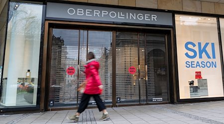 Eine Frau läuft vor Geschäftsöffnung an einem Eingang zum Kaufhaus Oberpollinger in München vorbei. / Foto: Peter Kneffel/dpa