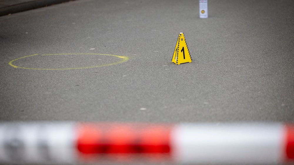 Markierungen der Spurensicherung auf dem Boden am Tatort des Angriffs auf zwei Kinder, einige Meter von einer Schule entfernt. Auf einem kleinen Parkplatz hat die Polizei Flatterband gespannt und alles abgesperrt. / Foto: Christoph Reichwein/dpa