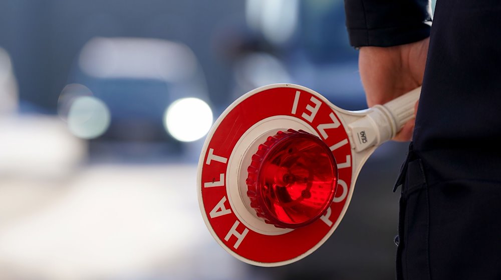 Ein Polizist hält eine Anhaltekelle in der Hand. / Foto: Marcus Brandt/dpa/Symbolbild