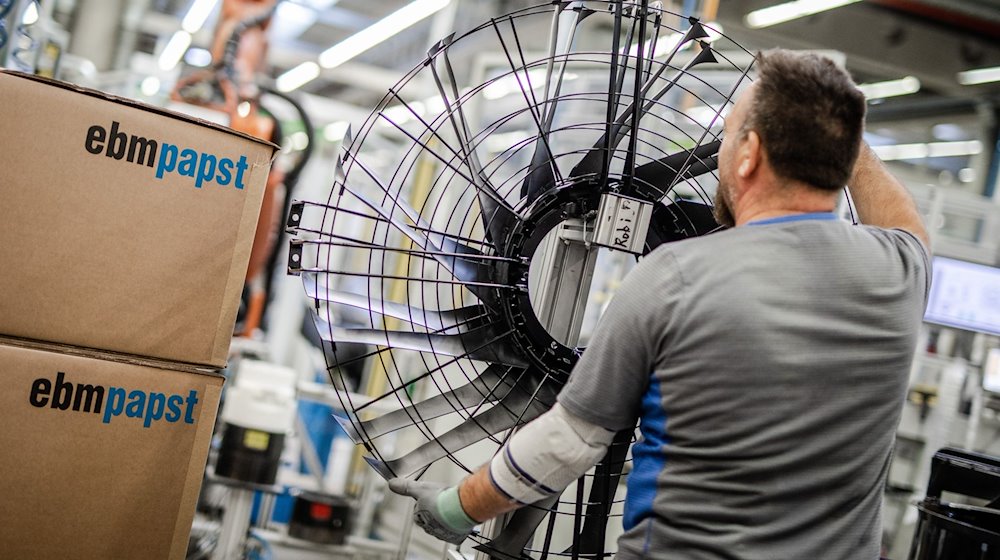 Ein Mitarbeiter des Elektromotoren- und Ventilatorenherstellers EBM-Papst, arbeitet in der Produktion an einem Ventilator. / Foto: Christoph Schmidt/dpa