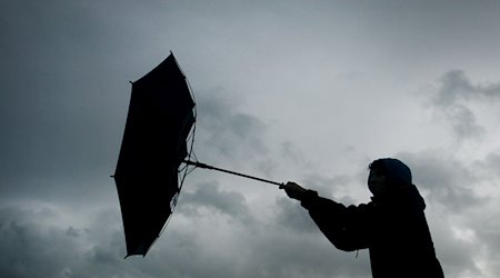 Von einer Windböe erfasst wird der Regenschirm eines Spaziergängers. / Foto: Karl-Josef Hildenbrand/dpa/Archivbild