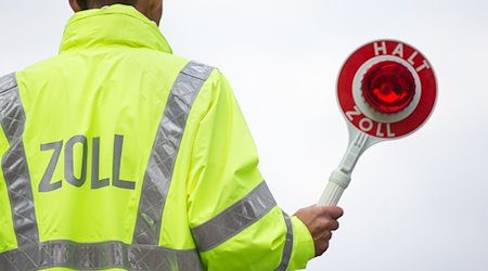 Ein Zollbeamter hält eine Kelle. / Foto: Friso Gentsch/dpa/Symbolbild