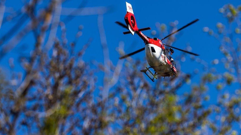 Ein Helikopter der DRF Luftrettung schwebt am Himmel über einem Waldstück. Für eine zügige und schonende Rettung aus unzugänglichen Gebieten ist der Hubschrauber mit einer fest installierten Winde ausgestattet. / Foto: Philipp von Ditfurth/dpa