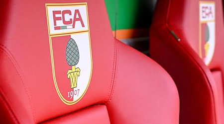 Das Logo des FC Augsburg ist auf Sitzen in der WWK-Arena zu sehen. / Foto: Harry Langer/dpa