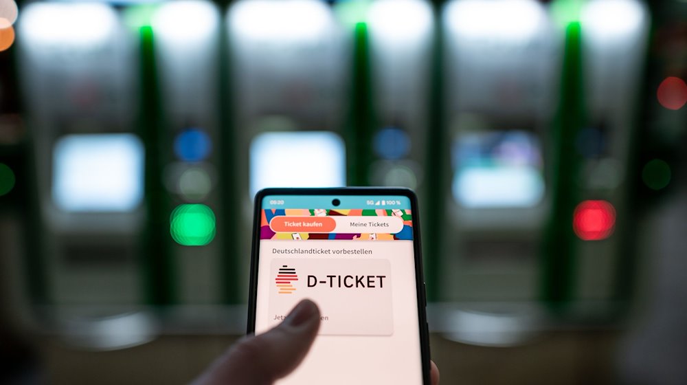 Ein Mann hält ein Mobiltelefon, auf dem das «D-Ticket» gekauft werden kann. / Foto: Fabian Strauch/dpa