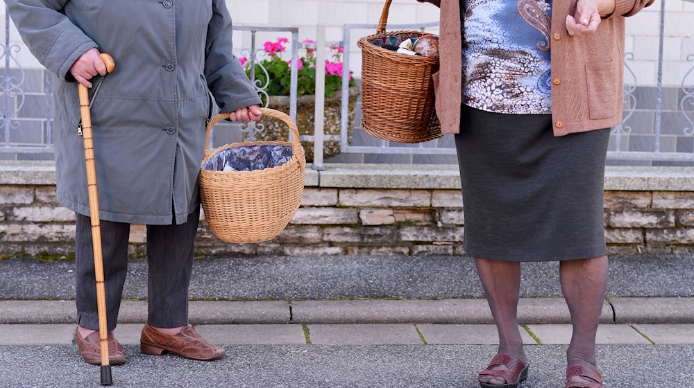 Zwei ältere Dame tragen nach einem Einkauf im mobilen Einkaufsladen in Hassenberg (Bayern) ihre Lebensmittel nach Hause. / Foto: David Ebener/dpa/Archivbild
