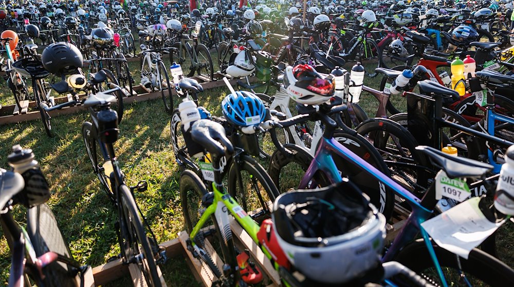 Fahrräder von teilnehmenden Triathleten des Datev Challenge Roth stehen in der Wechselzone von der Schwimmetappe zur Radetappe bereit. / Foto: Daniel Karmann/dpa