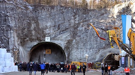 Arbeiter und Gäste stehen nach dem offiziellen Tunnelanschlag vor dem zukünftigen Nordportal des Kramertunnels. / Foto: Stephan Jansen/dpa