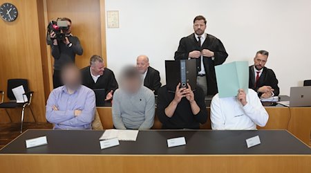 Der Hauptangeklagte (vorne r) sitzt in einem Gerichtssaal neben weiteren Angeklagten auf der Anklagebank. Er muss sich wegen Herbeiführung einer Sprengstoffexplosion und gefährlicher Körperverletzung verantworten. / Foto: Karl-Josef Hildenbrand/dpa