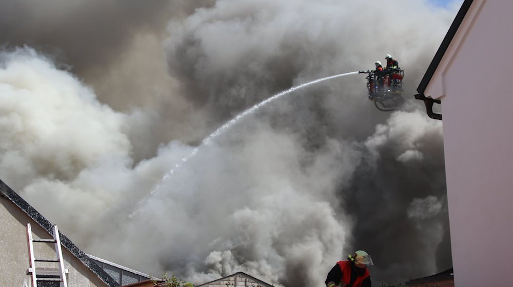 Einsatzkräfte der Feuerwehr versuchen den Brand im Dachstuhl einer Lagerhalle zu löschen. / Foto: Masching/NEWS5/dpa