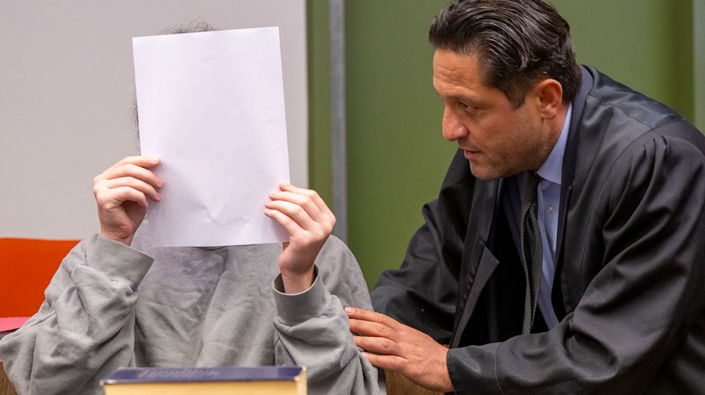 Ein 21-Jähriger Mann, der seine Mutter mit einer Axt erschlagen haben soll, unterhält sich im Gerichtssaal des Landgericht München I mit seinem Anwalt Ömer Sahinci (r). / Foto: Peter Kneffel/dpa