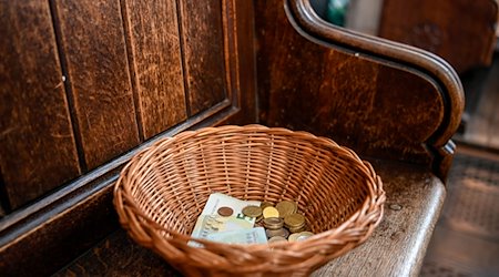 Ein Korb mit Geldscheinen und Münzen steht in einer Kirche. / Foto: Elisabeth Edich/dpa/Archivbild