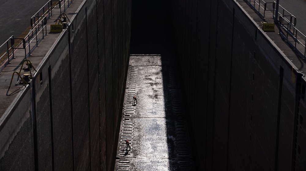 Zwei Arbeiter sind in der Schleuse Eckersmühlen als Silhouetten im Sonnenlicht zu erkennen. Der Main-Donau-Kanal ist ab Montag wegen umfangreichen Arbeiten für rund drei Wochen für die Schifffahrt gesperrt. / Foto: Nicolas Armer/dpa