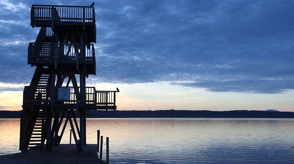 Im Sonnenaufgang steht der hölzerne Sprungturm des Strandbades am Ammersee. / Foto: Karl-Josef Hildenbrand/dpa