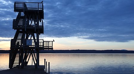 Im Sonnenaufgang steht der hölzerne Sprungturm des Strandbades am Ammersee. / Foto: Karl-Josef Hildenbrand/dpa