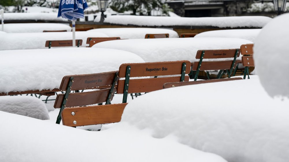 Schnee liegt auf Tischen und Stühlen in einem Biergarten am Walchensee. / Foto: Peter Kneffel/dpa