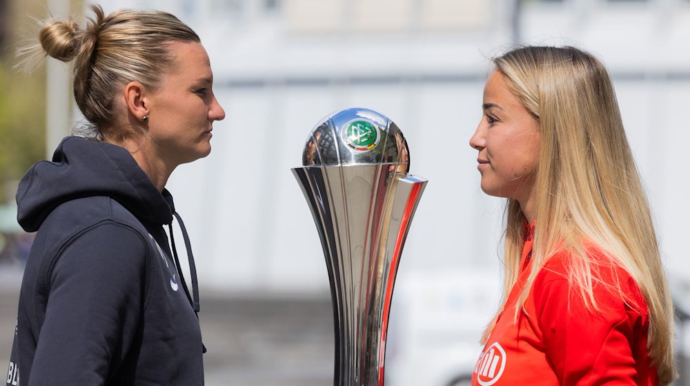 Alexandra Popp (l) vom VfL Wolfsburg und Giulia Gwinn vom FC Bayern München stehen neben dem Pokal vor dem Deutschen Sport und Olympiamuseum. / Foto: Rolf Vennenbernd/dpa