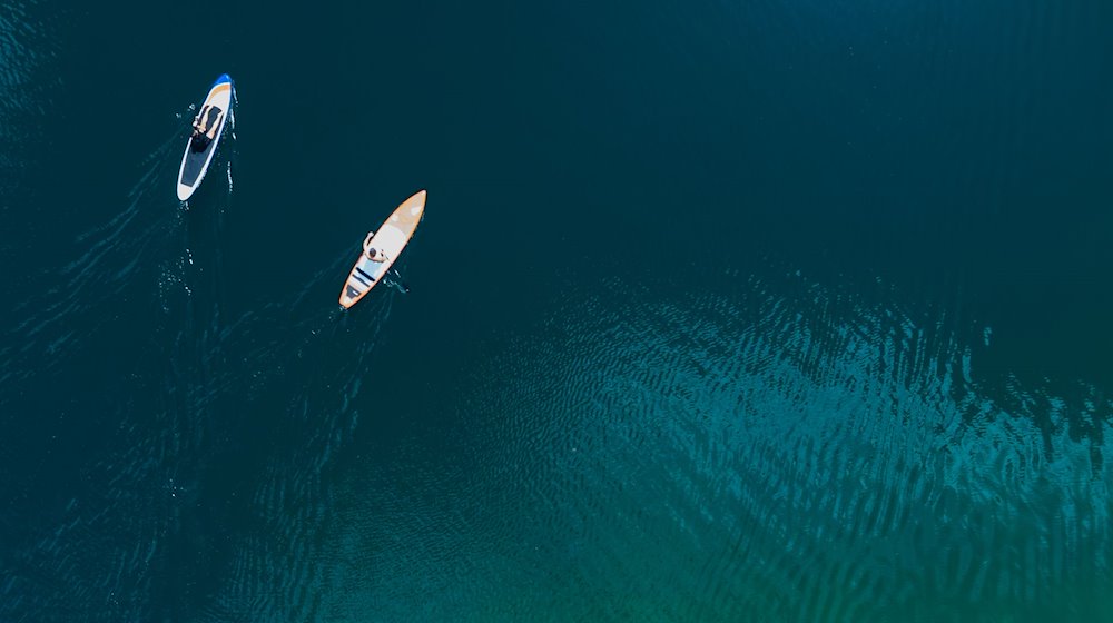 Ein Mann und eine Frau genießen das schöne Wetter mit ihren SUPs (Stand up Paddle Boards) auf dem Langwieder See. / Foto: Sven Hoppe/dpa/Archivbild