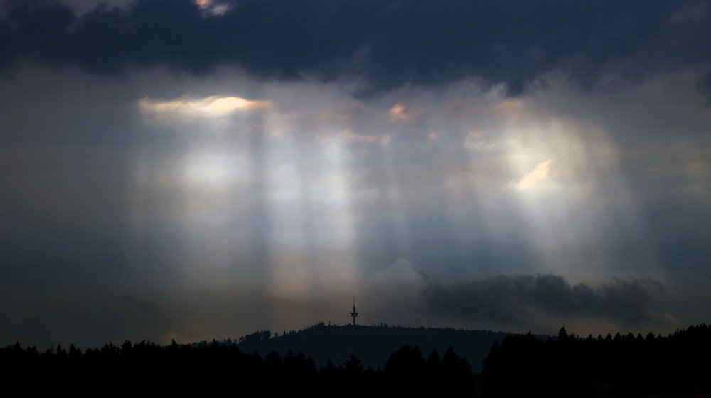 Sonnenstrahlen dringen am Abend durch Wolkenlücken über dem Fernmeldeturm Weichberg. / Foto: Karl-Josef Hildenbrand/dpa