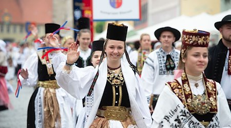 In traditioneller Tracht laufen Teilnehmer eines Trachtenumzuges der Siebenbürger Sachsen durch die Altstadt von Greding. / Foto: Timm Schamberger/dpa