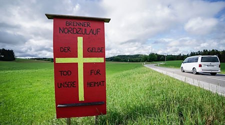 Ein Protestschild mit der Aufschrift «Brenner Nordzulauf - Der gelbe Tod für unsere Heimat» einer Bürgerinitiative steht auf einer Wiese der geplanten Bahntrasse. / Foto: Uwe Lein/dpa