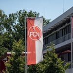 Fahnen mit dem FCN-Logo wehen vor dem Vereinsgebäude. / Foto: Daniel Karmann/dpa