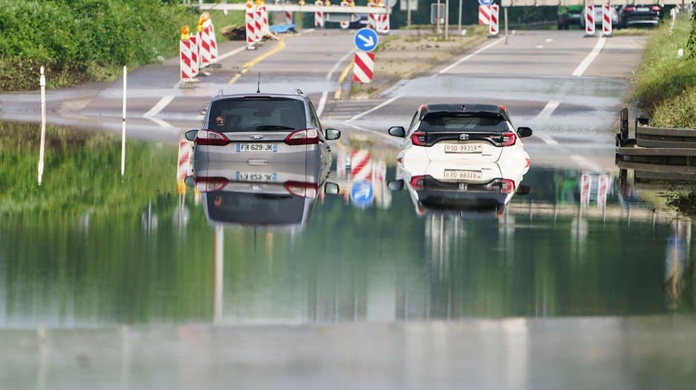 Zwei Autos stehen unter einer Saarbrücke im Stadtteil Schönbach im Hochwasser. / Foto: Andreas Arnold/dpa