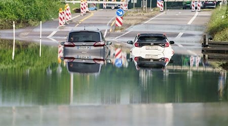 Zwei Autos stehen unter einer Saarbrücke im Stadtteil Schönbach im Hochwasser. / Foto: Andreas Arnold/dpa