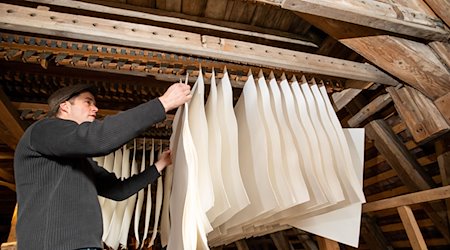 Papier hängt zum Trocknen im Nebengebäude der Werkstatt der historischen Papiermühle in Homburg. / Foto: Daniel Karmann/dpa/Archiv