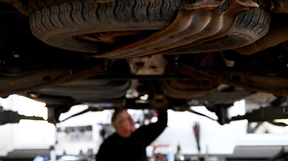 Ein Kfz-Mechaniker überprüft den Unterboden eines Autos. / Foto: Pia Bayer/dpa