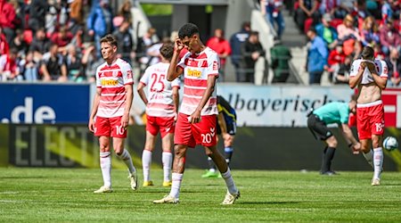 Die Mannschaft von Regenburg steht nach dem mit 0:1 verlorenen Spiel gegen Saarbrücken auf dem Rasen. / Foto: Armin Weigel/dpa