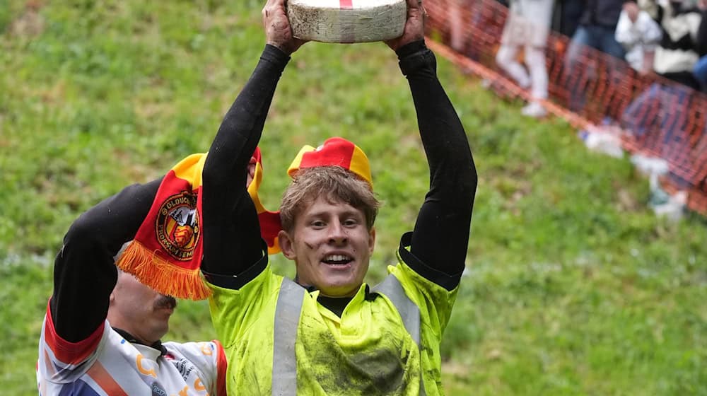 Tom Kopke aus Deutschland, der Sieger des ersten Rennens, hebt einen Double-Gloucester-Käse, nachdem er am jährlichen Käserennen "Cheese-Rolling" bei Cooper's Hill teilgenommen hat. / Foto: Jacob King/PA Wire/dpa