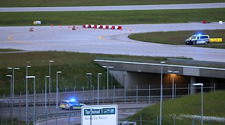 Klimaaktivisten haben sich am frühen Morgen auf einer Zufahrt für Start- und Landebahnen am Flughafen Franz-Josef-Strauß festgeklebt. / Foto: Karl-Josef Hildenbrand/dpa